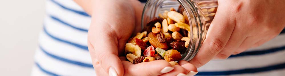 A woman pouring nuts from a jar into her hand