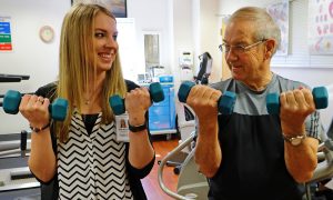 A physical therapist showing an elderly man how to use 5 lb weights