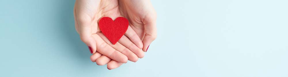 A person holding a piece of heart shaped felt in their cupped hands