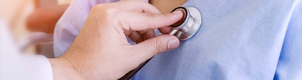 A doctor using a stethescope to listen to someone's heart