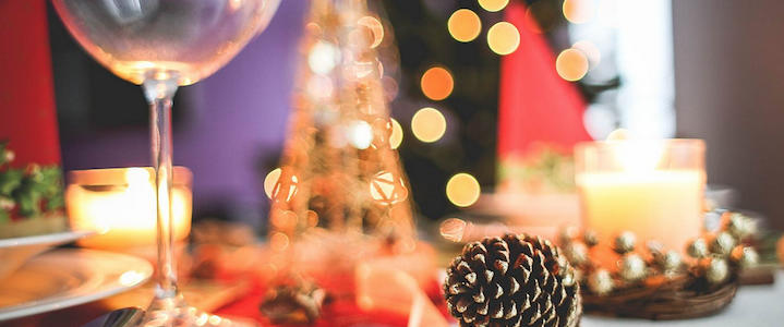 A dining table decorated with holiday decorations, lights, candles and pinecones