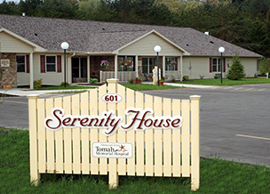 The front of Serenity House with their sign on a fence