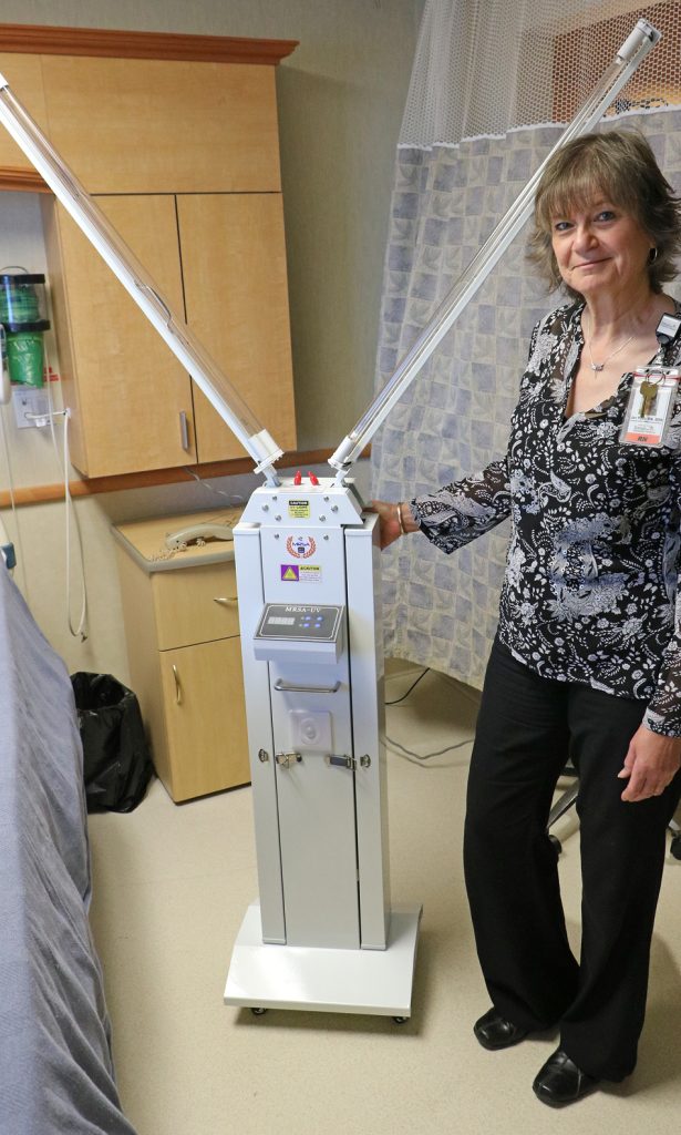 Tomah Health infection preventionist poses with a sanitation robot