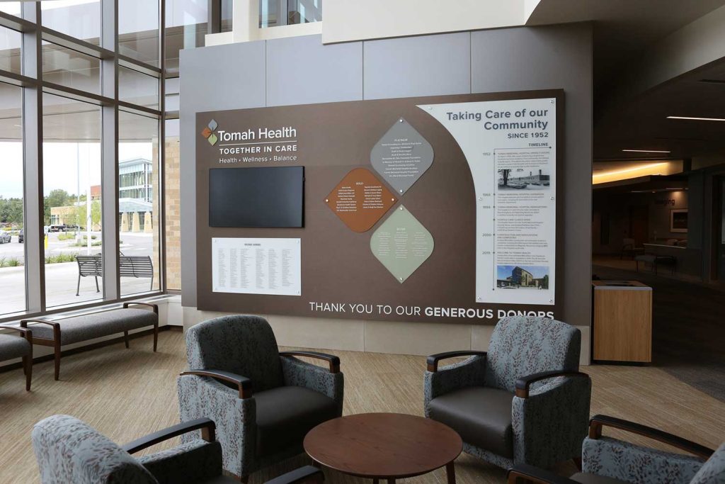 A small waiting area next to large windows and a display on a wall with donor information