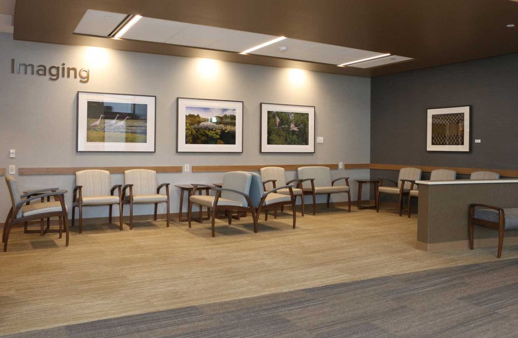 A hospital waiting room with many chairs and art on the walls
