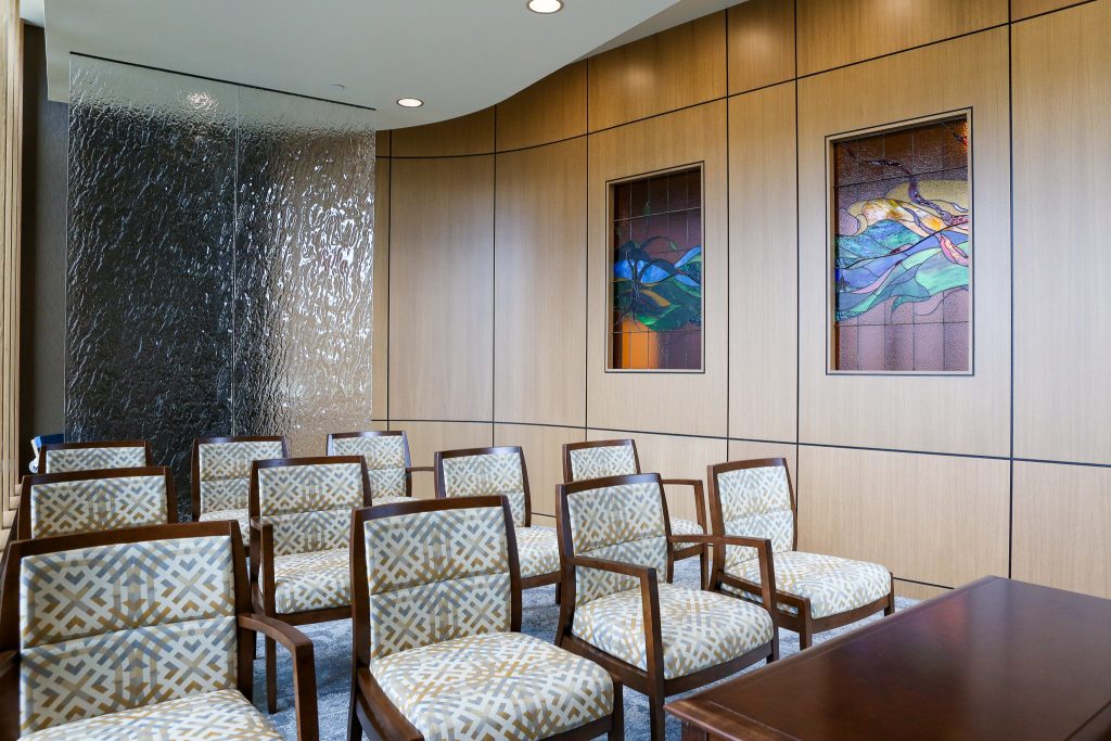 A few rows of chairs in a small room with stained glass windows