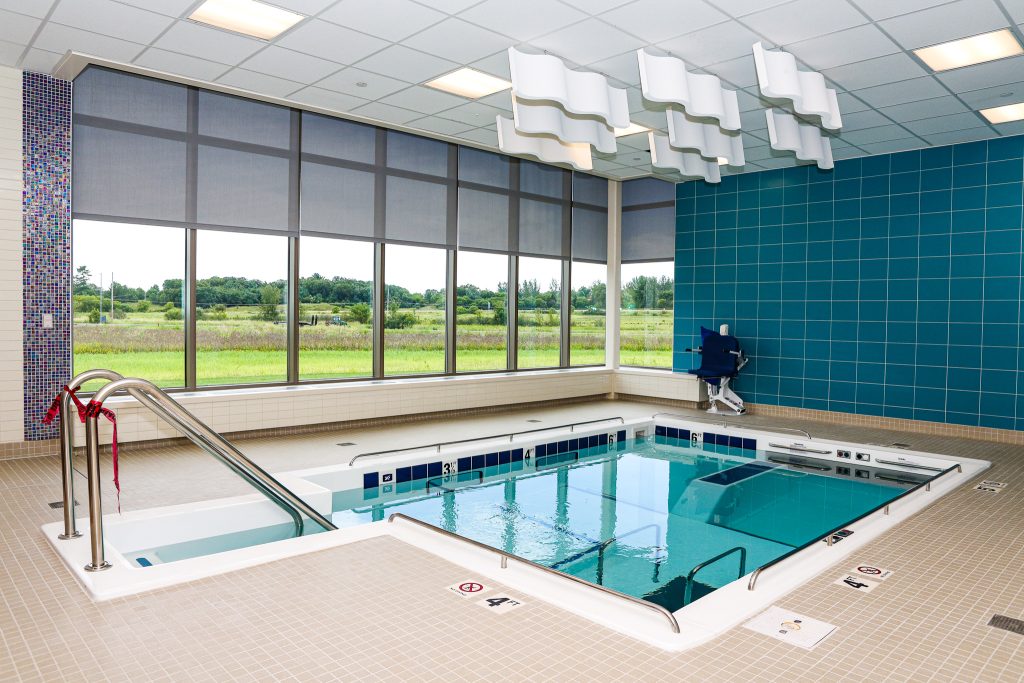 A large therapy pool next to floor to ceiling windows