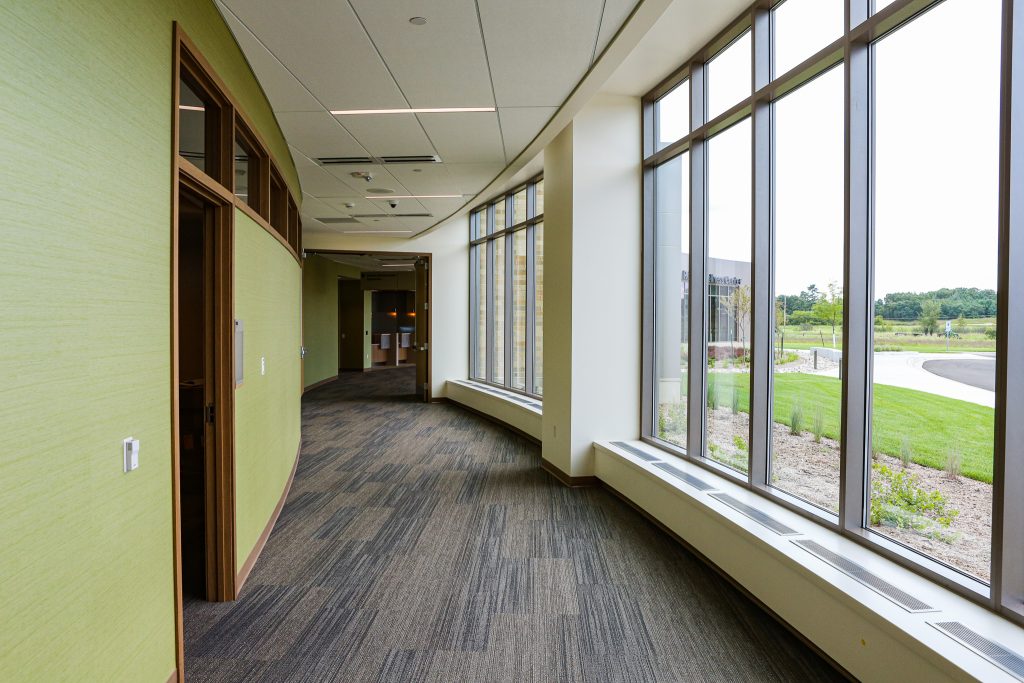 A hallway with doorways on the left side and windows on the right