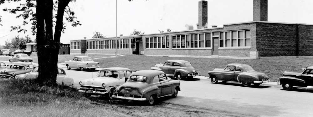 A black and white photo of Tomah Memorial Hospital from c. 1950 with cars parked outside
