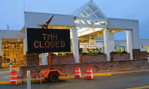 A highway directional sign announced TMH Closed in front of Tomah Memorial Hospital