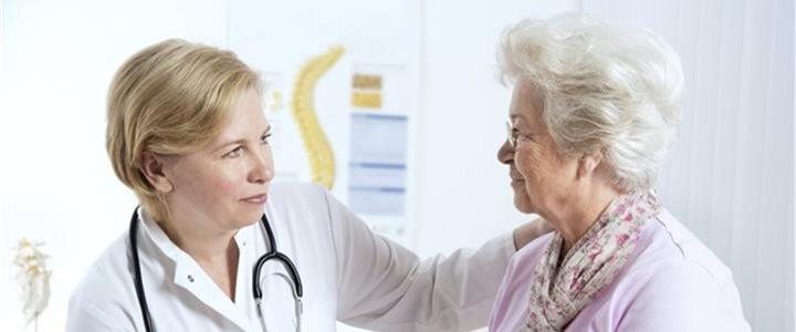 An elderly woman speaking with a femail doctor in an office