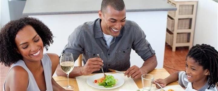 An African-American family sitting at their dining room table eating a meal