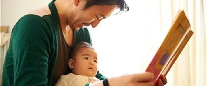 An asian father reading to a baby on his lap