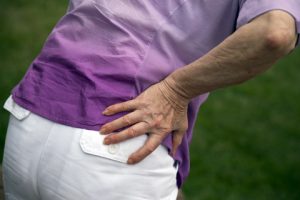 An elderly woman holding her hip in pain