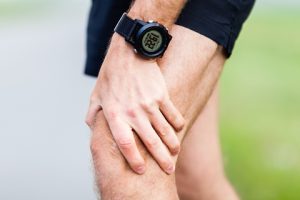 A runner gripping his knee in pain