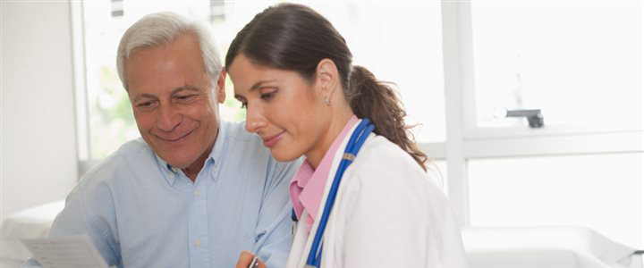 An older man looking over paperwork with his female doctor