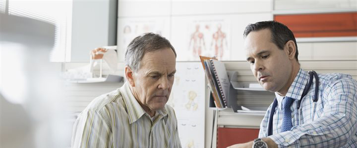 An elderly man talking with a doctor in an office