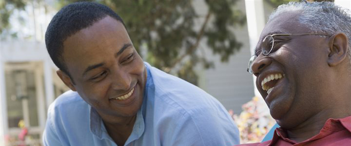 A younger man and an older man sitting outside laughing together