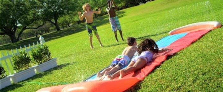 Children playing on a slip-n-slide in a backyard on a bright summer day