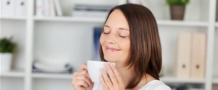 A woman enjoying a cup of tea in a living room or office