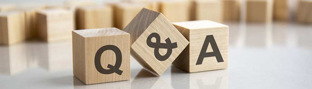 Q and A - an abbreviation of wooden blocks with letters on a gray background. Reflection of the Q and A caption on the mirrored surface of the table. Selective focus.