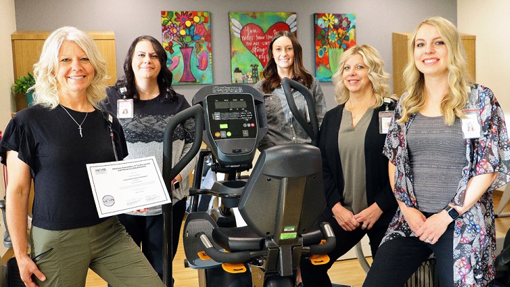 Tomah Health cardiac rehab staff standing with a rehab machine